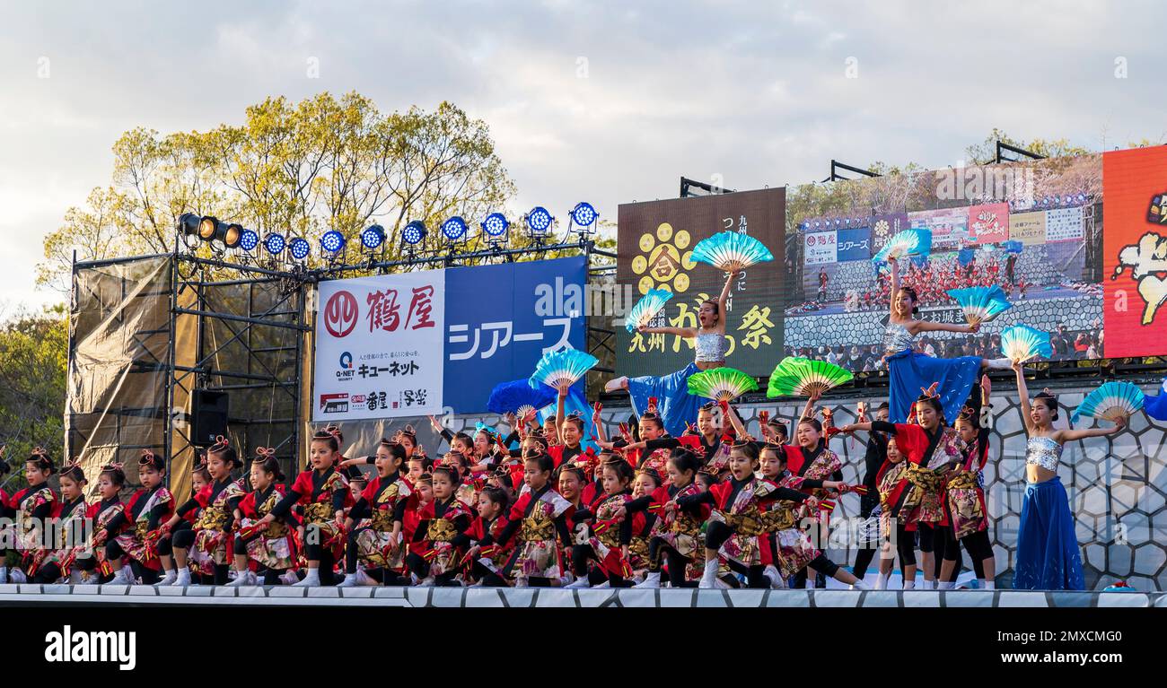 Squadra giapponese di danzatrici Yosakoi bambini ballare e tenere naruko e tifosi sul palco all'aperto al festival Kyusyu Gassai a Kumamoto. Foto Stock