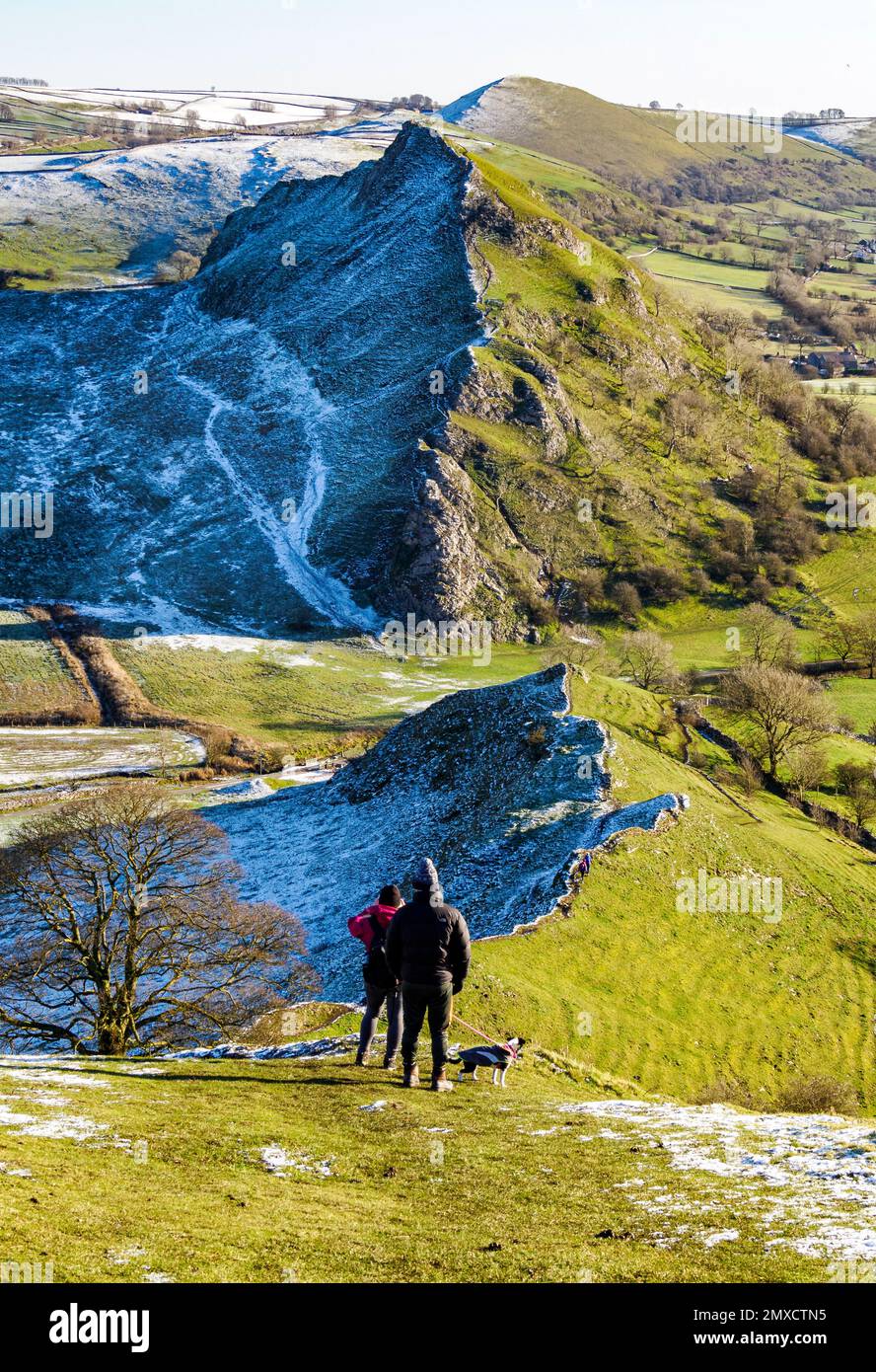 Gli escursionisti e il loro cane ammirano la vista invernale da Chrome Hill fino alla cima prominente di Parkhouse Hill nel Derbyshire Peak District UK Foto Stock