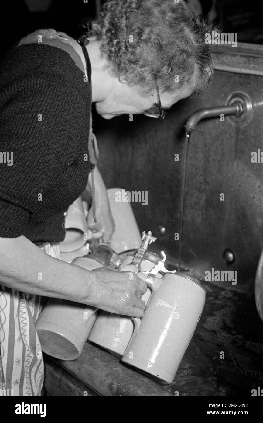 Kellnerin leert Bierkrüge aus im Münchner Hofbräuhaus am Platzl, 1957. Cameriera che svuota le tazze di birra al Hofbräuhaus di Monaco a Platzl, 1957. Foto Stock