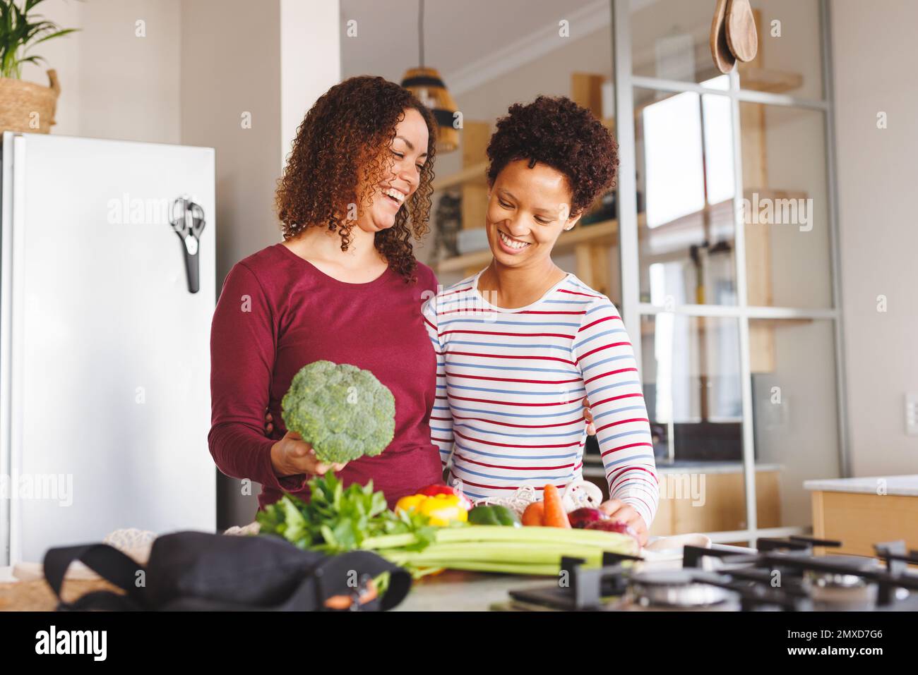 Coppia lesbica diversa felice disimballare i generi alimentari in cucina Foto Stock