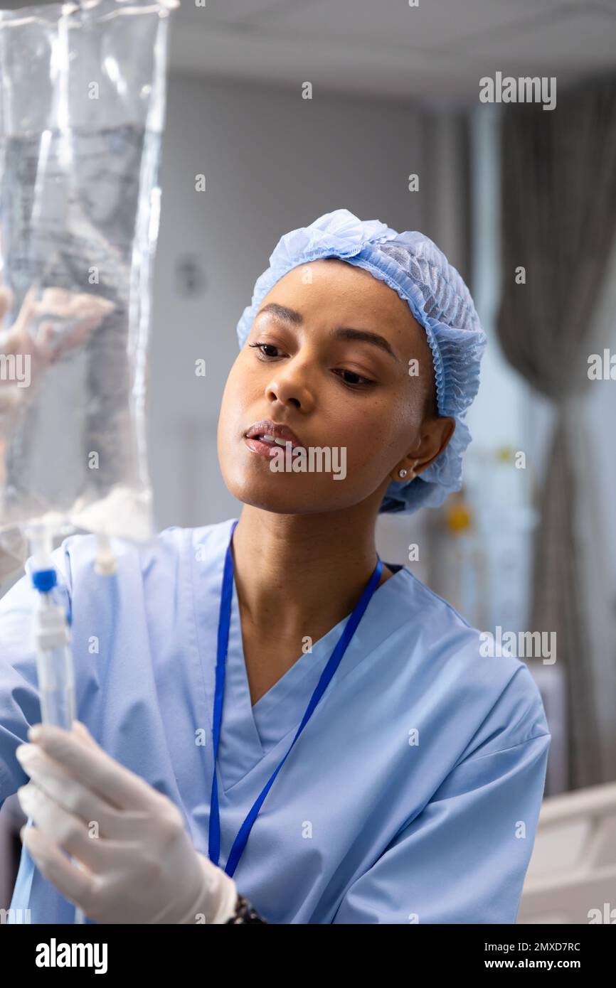Primo piano di una dottoressa biraciale che lavora in ospedale, cambiando fleboclisi Foto Stock