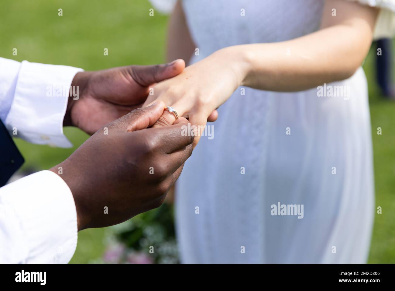 A metà dello sposo diverso che mette l'anello sul dito della sposa alle nozze esterne, spazio della copia Foto Stock