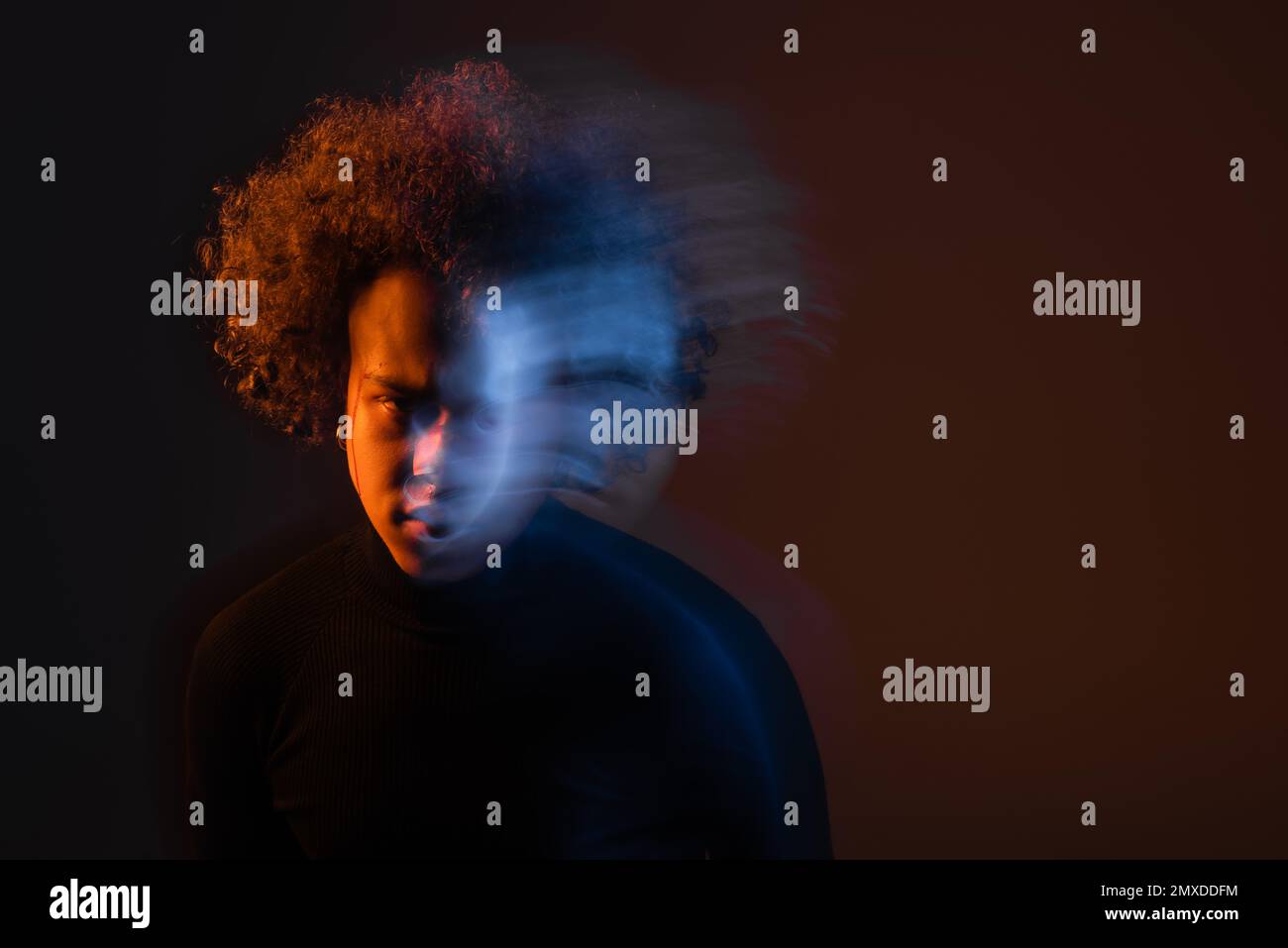 lunga esposizione di afro-americano stressato con disturbo bipolare e faccia sanguinante su sfondo scuro con luce arancione e blu, immagine stock Foto Stock
