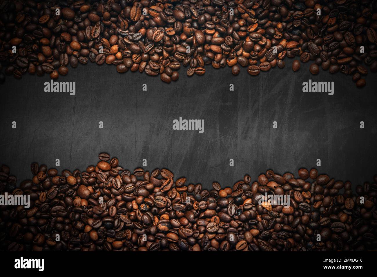 Grande gruppo di chicchi di caffè tostati su una lavagna vuota con spazio per le copie. Composizione orizzontale. Foto Stock