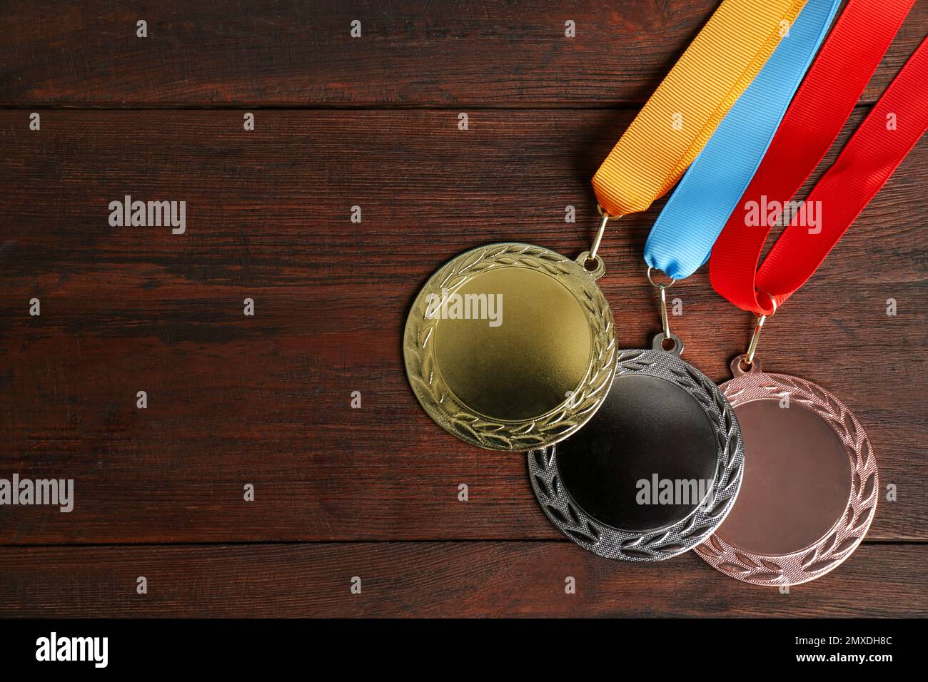 Medaglie d'oro, d'argento e di bronzo su sfondo ligneo, giacitura piatta. Spazio per il design Foto Stock