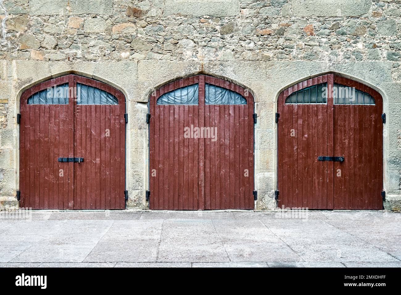 Porte di legno marrone sulle pareti circondate da pietre in design medievale nascondono cose misteriose dai visitatori in arrivo. Esterno del luogo medievale Foto Stock