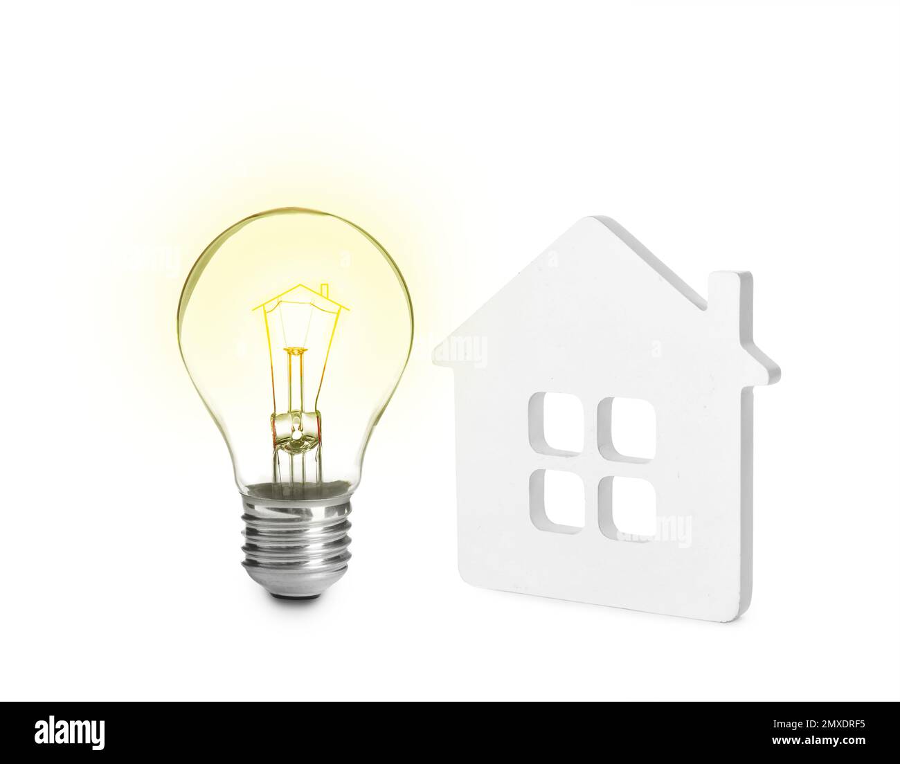 Lampadina luminosa e piccolo modello di casa su sfondo bianco. Concetti di efficienza energetica, prestito, proprietà o idea di business Foto Stock