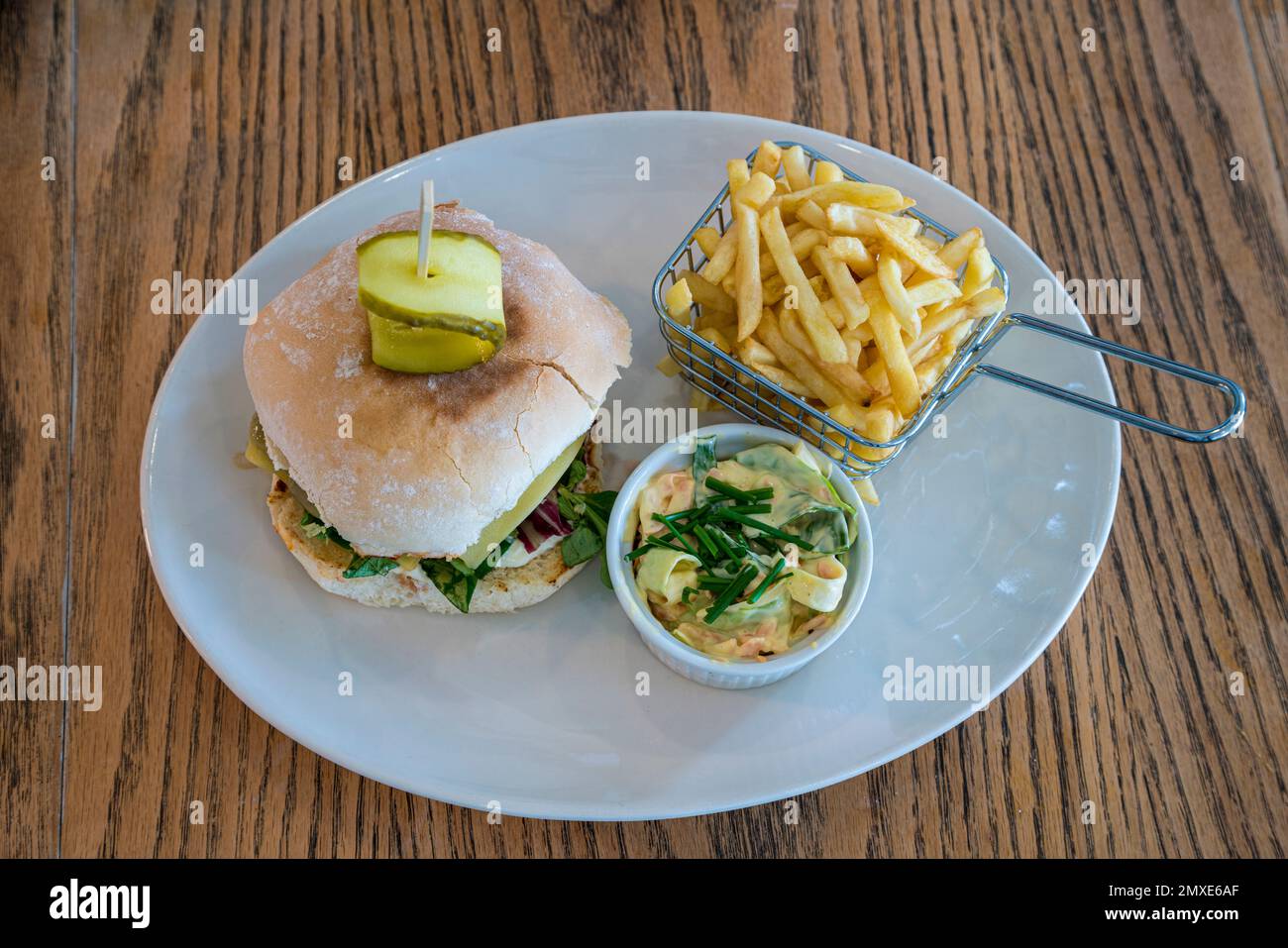 Caffè hamburger interno con patatine e coleslaw servito su un piatto bianco Foto Stock