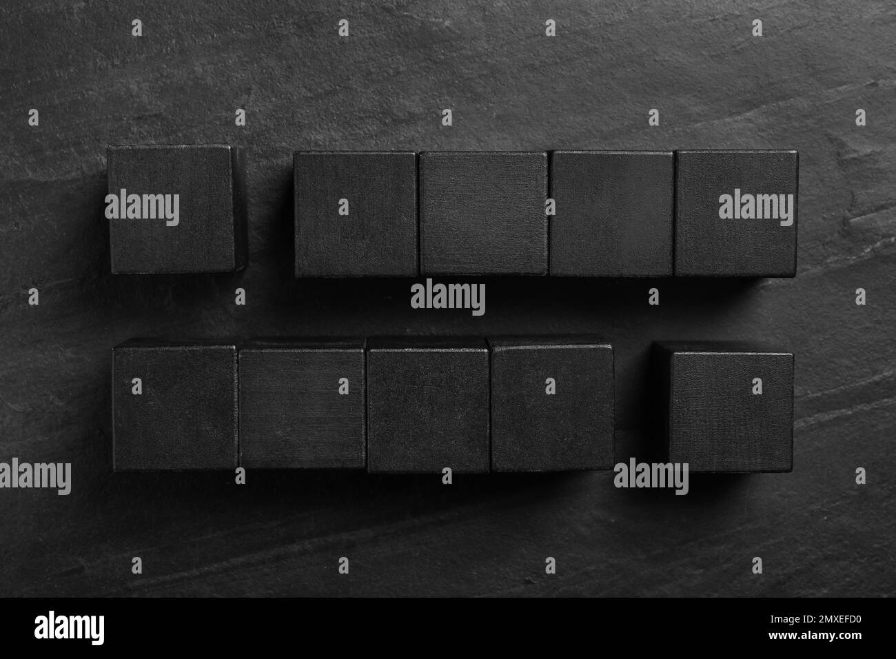 Composizione piatta con cubetti su fondo in ardesia nera. Principio di Pareto Foto Stock