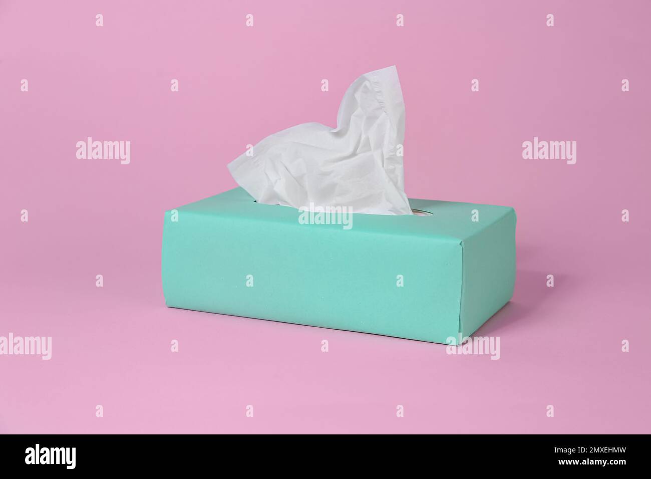 Scatola con fazzolettini di carta su sfondo rosa Foto Stock