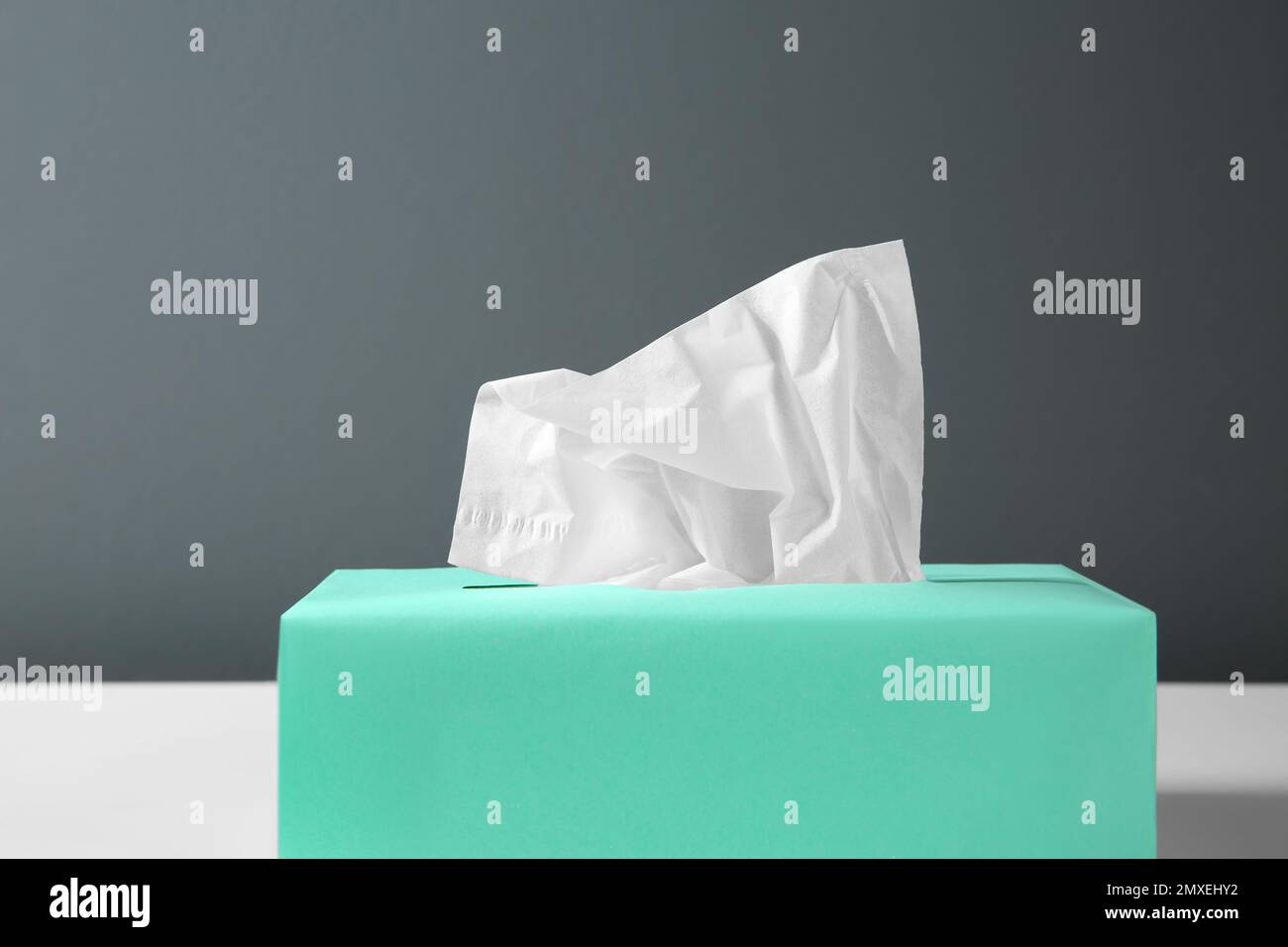 Scatola con fazzolettini di carta sul tavolo su sfondo nero, primo piano Foto Stock