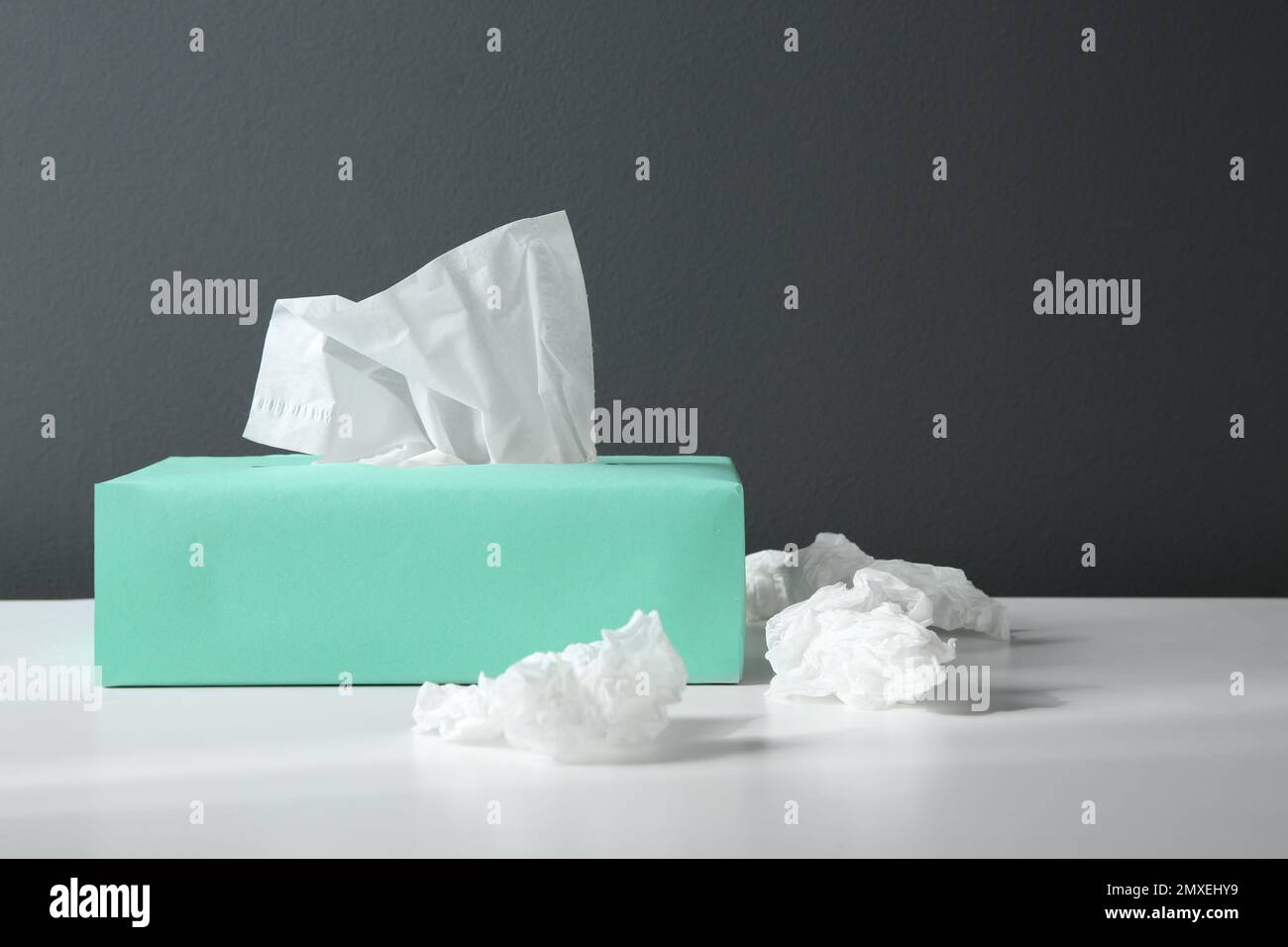 Fazzolettini di carta usati e scatola su tavolo bianco Foto Stock