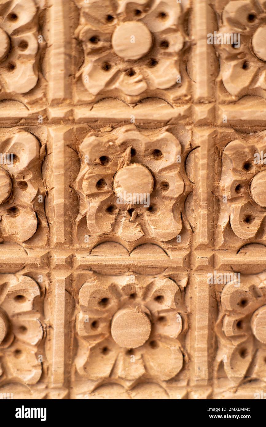 Una texture di muro di pietra con elementi floreali intagliati Foto Stock