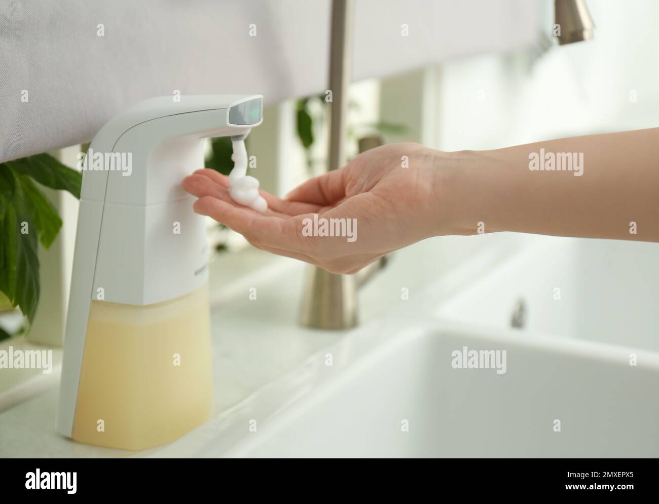 Donna che usa un dispenser automatico di sapone in cucina, primo piano Foto  stock - Alamy