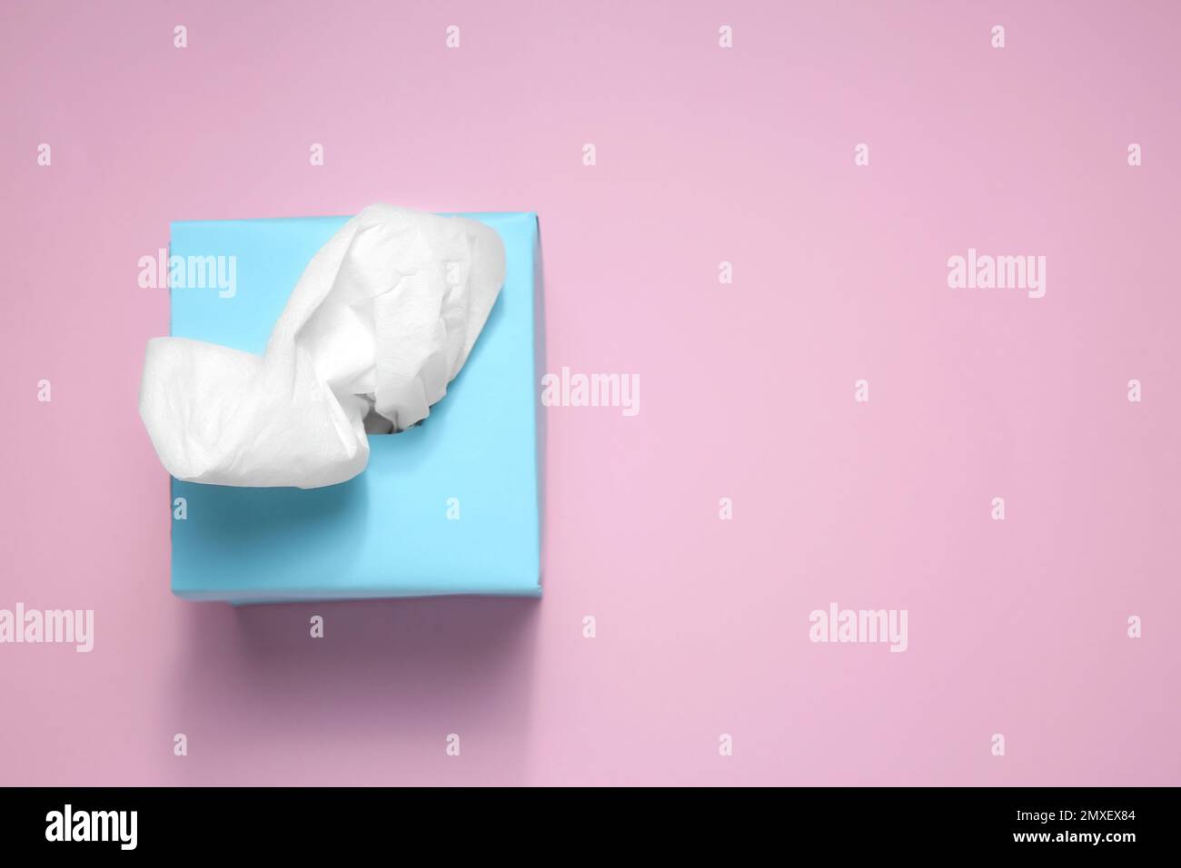 Scatola con fazzolettini di carta su sfondo rosa, vista dall'alto. Spazio per il testo Foto Stock