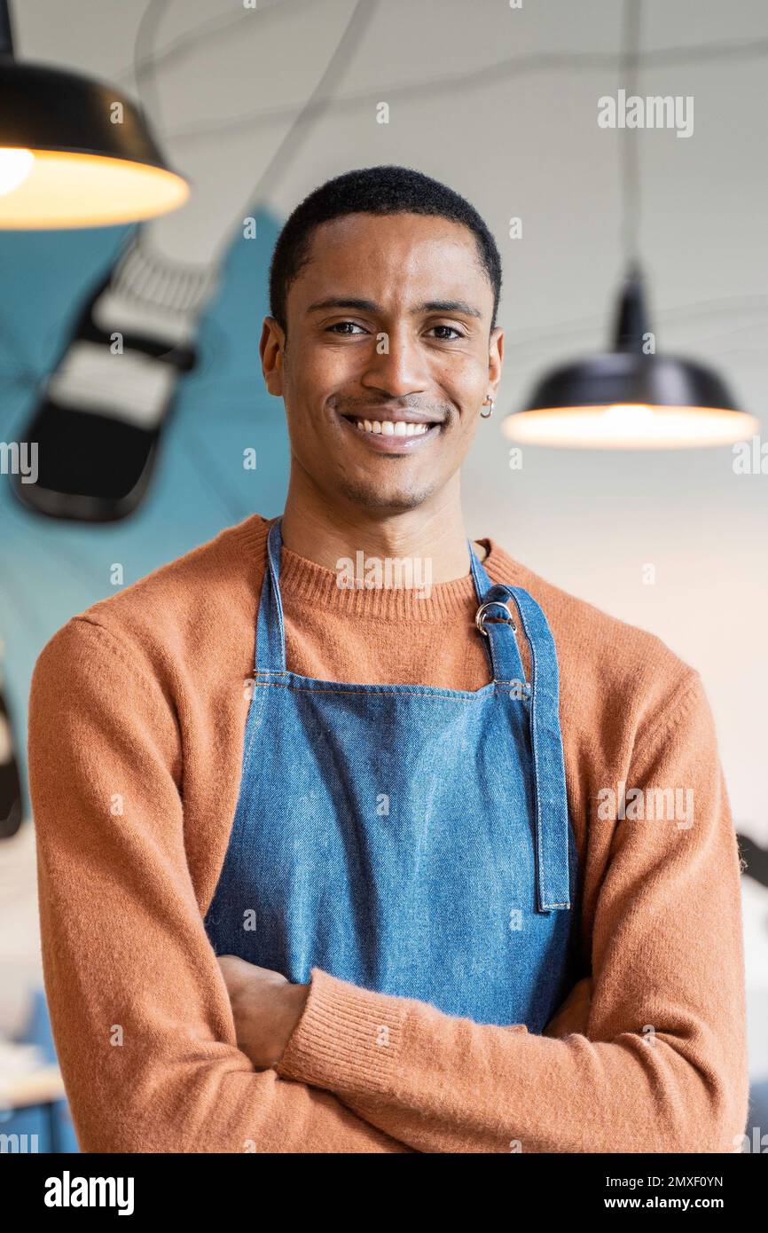 Sorridente proprietario o cameriere in uniforme da lavoro in piedi in caffetteria moderna o pub ristorante - concetto di ricerca di lavoro - lavorare in catering - verticale ritratto Foto Stock