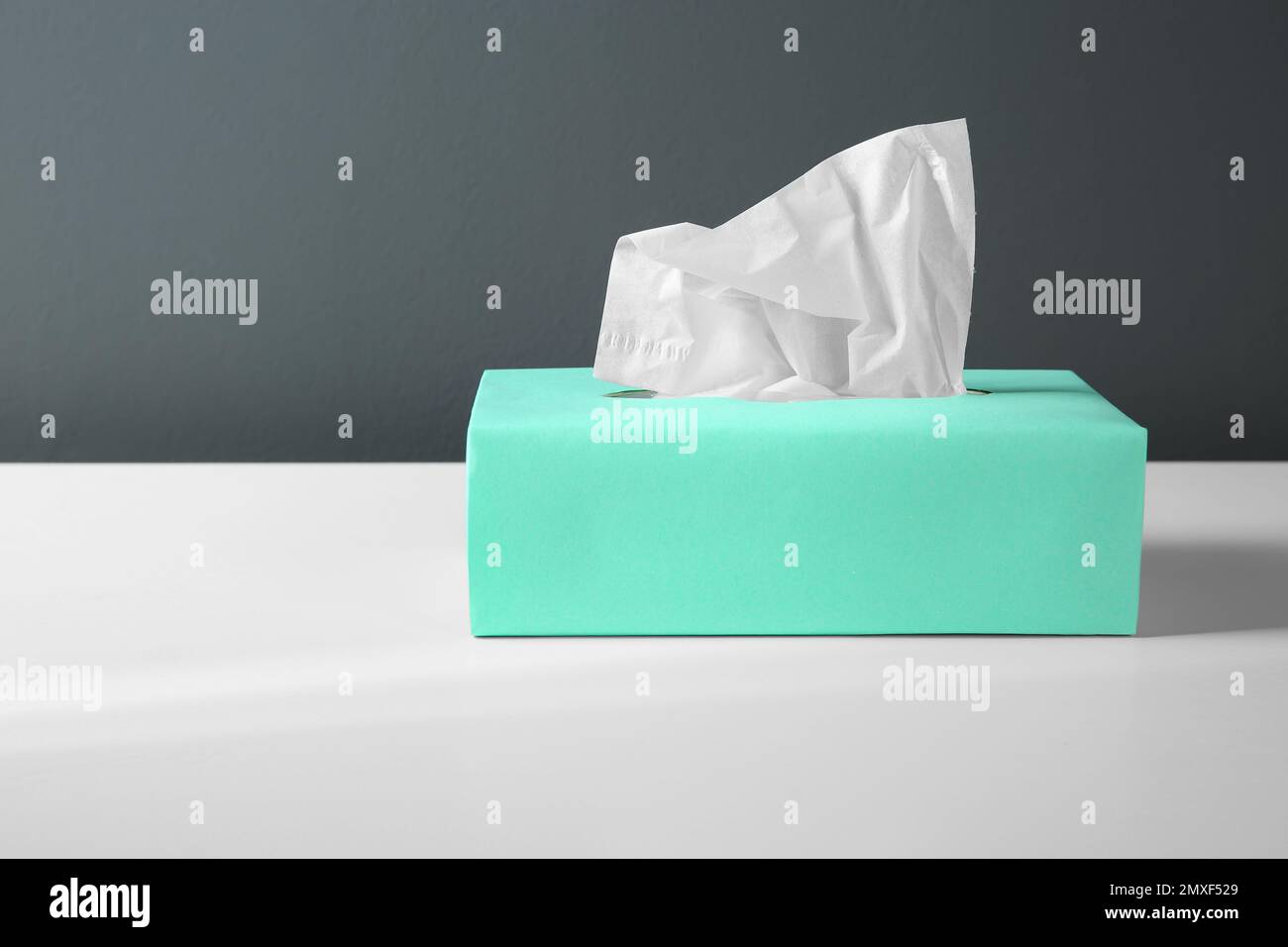 Scatola con fazzolettini di carta su tavolo bianco Foto Stock