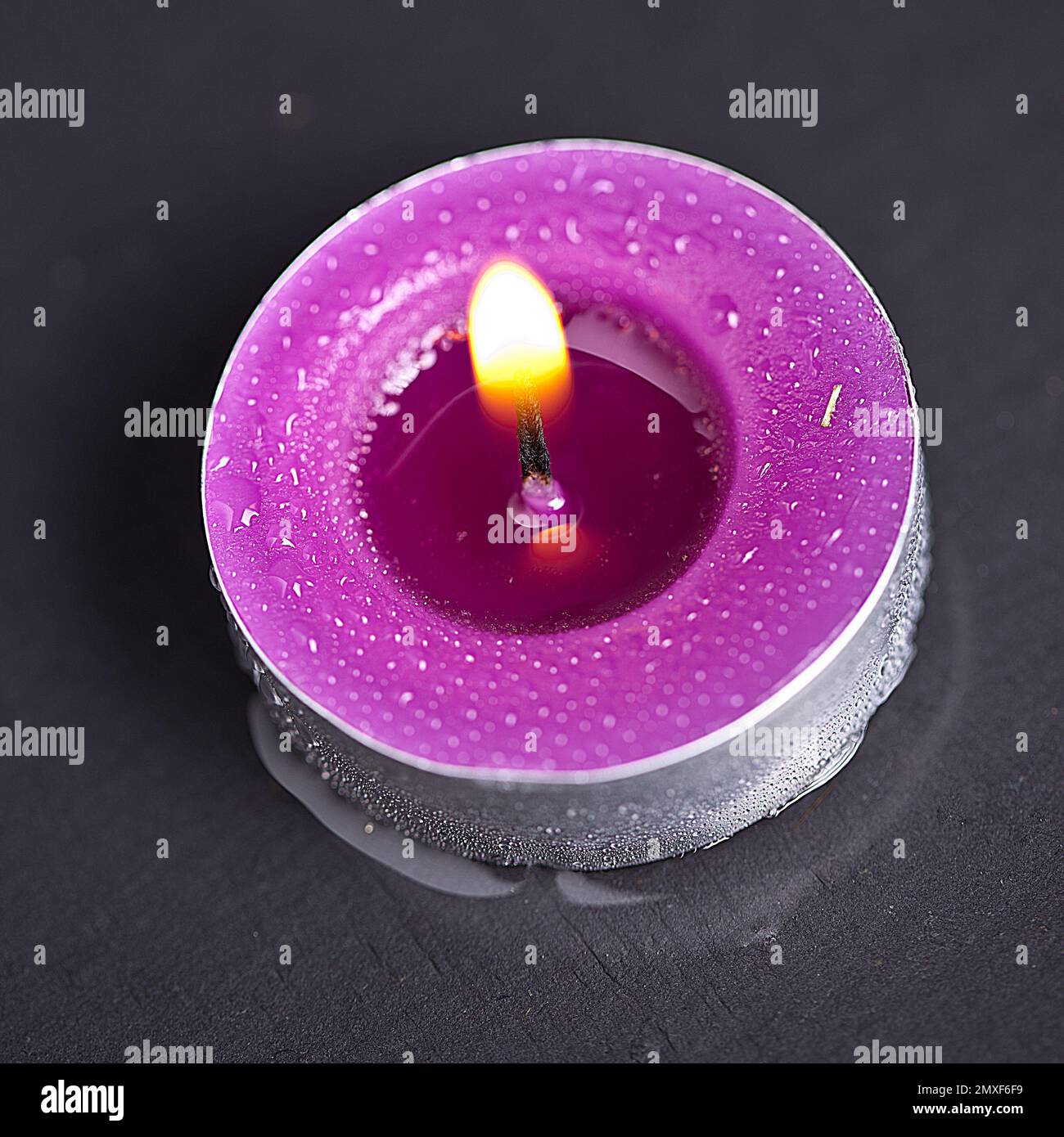 candela con gocce d'acqua su pietra nera Foto Stock