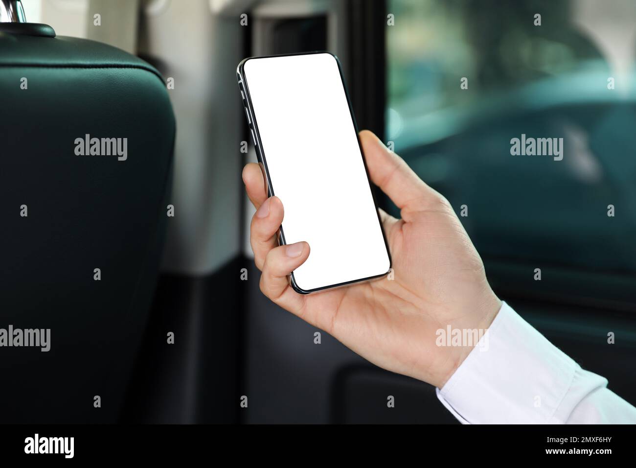 Uomo che tiene il telefono cellulare con schermo vuoto in salone auto, primo piano Foto Stock