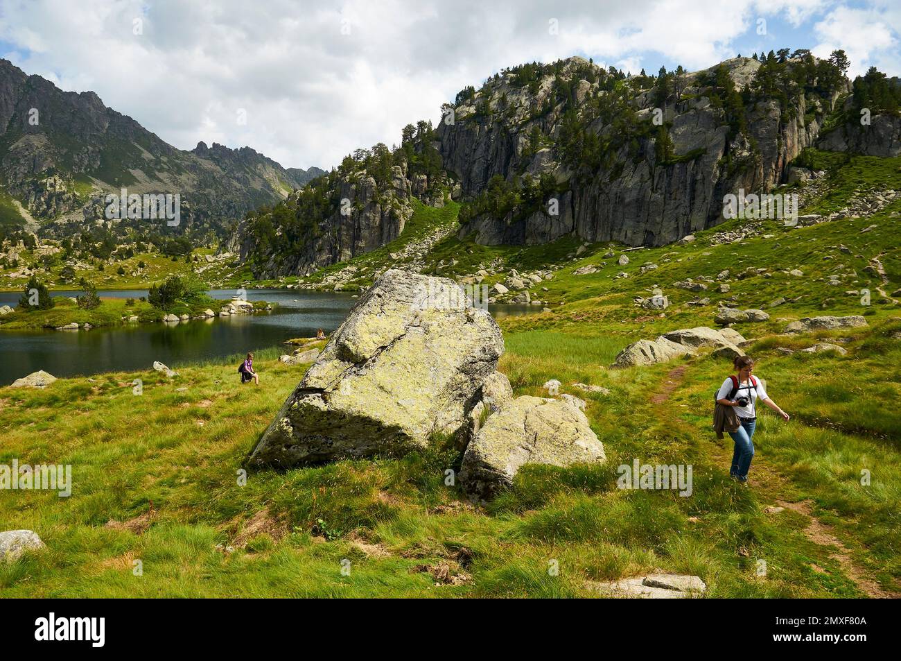 Escursionisti al lago Estanh Plan nel Parco Nazionale di Aigüestortes i Estany de Sant Maurici (valle di Aran, Lleida, Pirenei, Cataluña, Spagna) Foto Stock