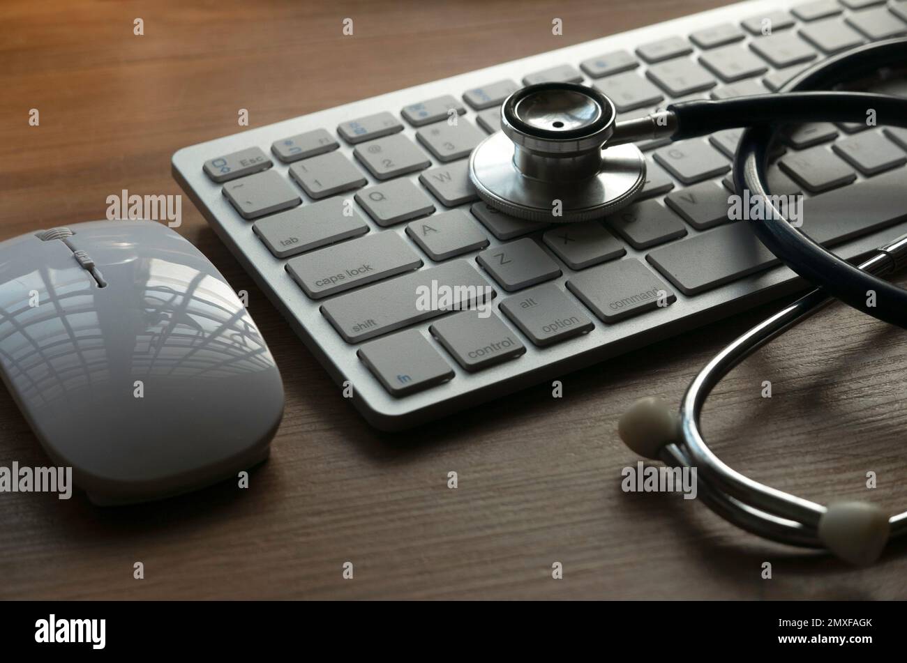 Stetoscopio, mouse e tastiera di computer su un fondo di legno .concetto di tecnologia dell'informazione medica e diagnostica e riparazione di computer. Foto Stock
