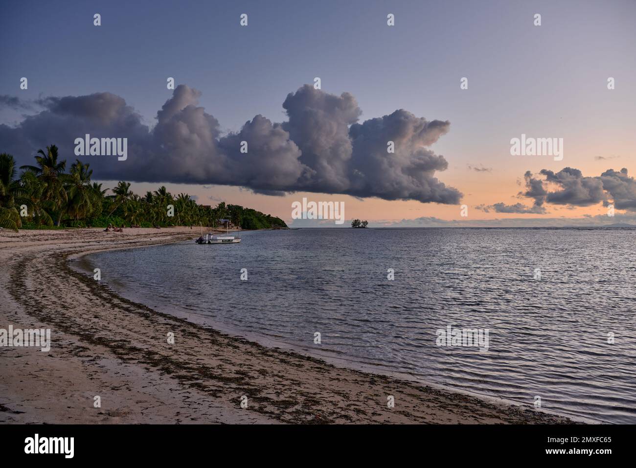 Nuvole e sole tramontano sulla spiaggia di Anse Reunion, la Digue, Seychelles Foto Stock