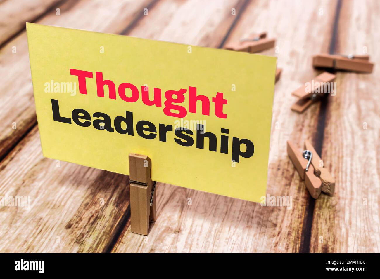 Scheda del messaggio concettuale che mostra la leadership di pensiero su una tavola di legno di shabby. Spilla di legno o presa di legno naturale che tiene nota di carta gialla. Foto Stock