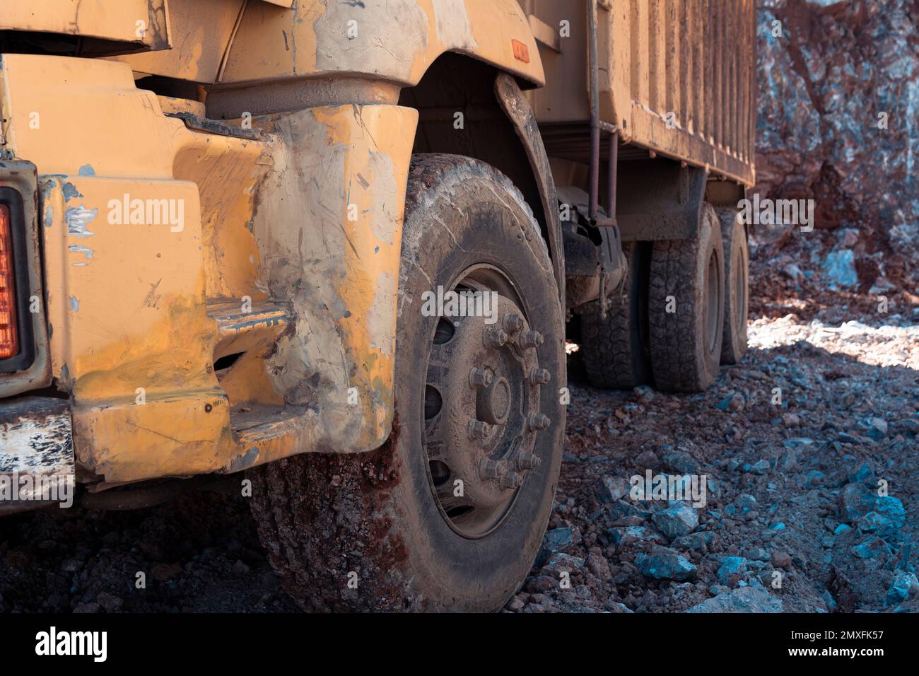 Macchine pesanti lavorano nel cantiere. Suolo roccioso di radura per costruzione in Turchia. Ruote di un camion giallo vintage. Foto Stock