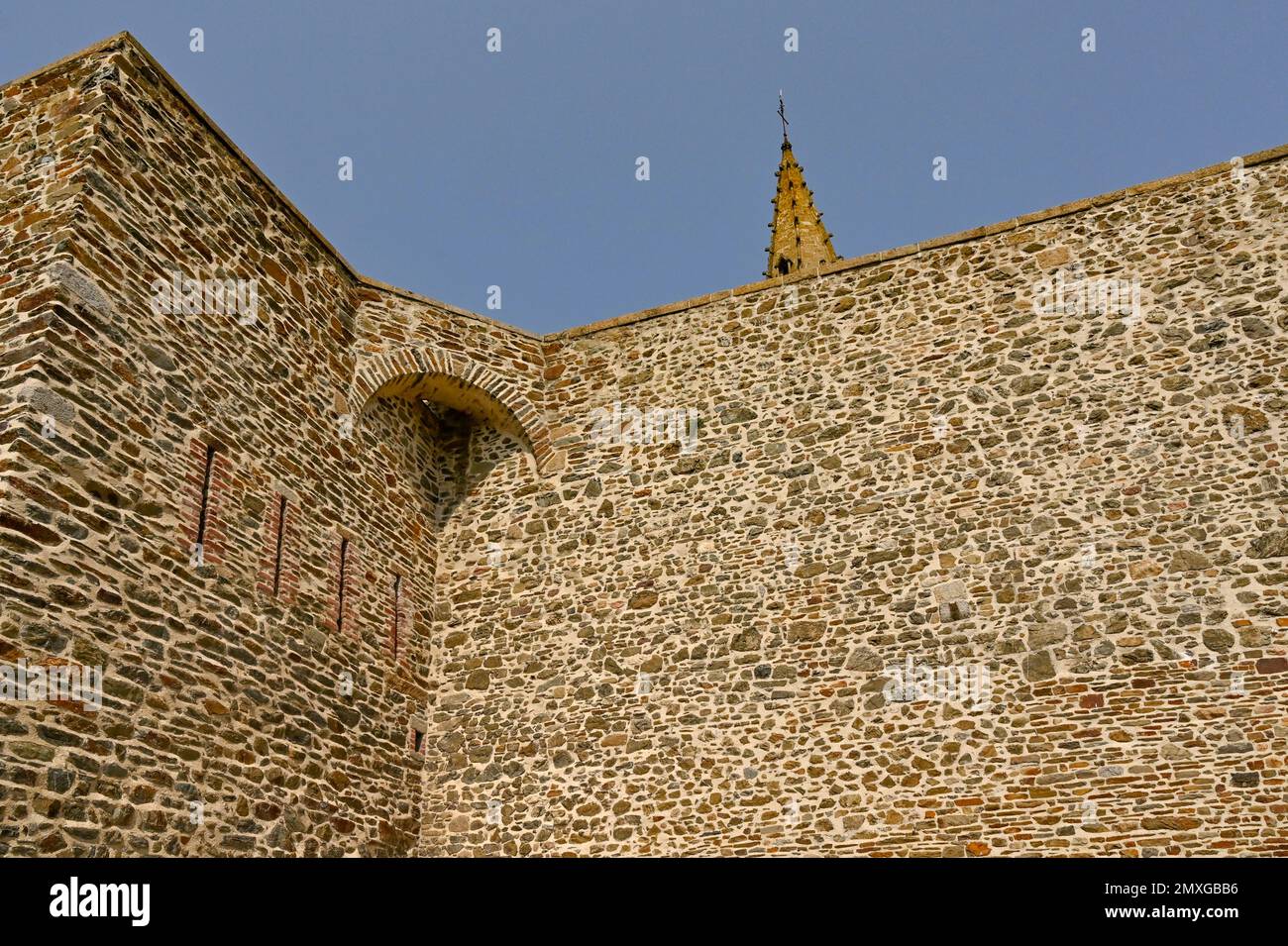 Dettagli delle mura fortificate di Granville, con la guglia di Notre-Dame che peping sulla fortificazione, Noramndy, Francia Foto Stock