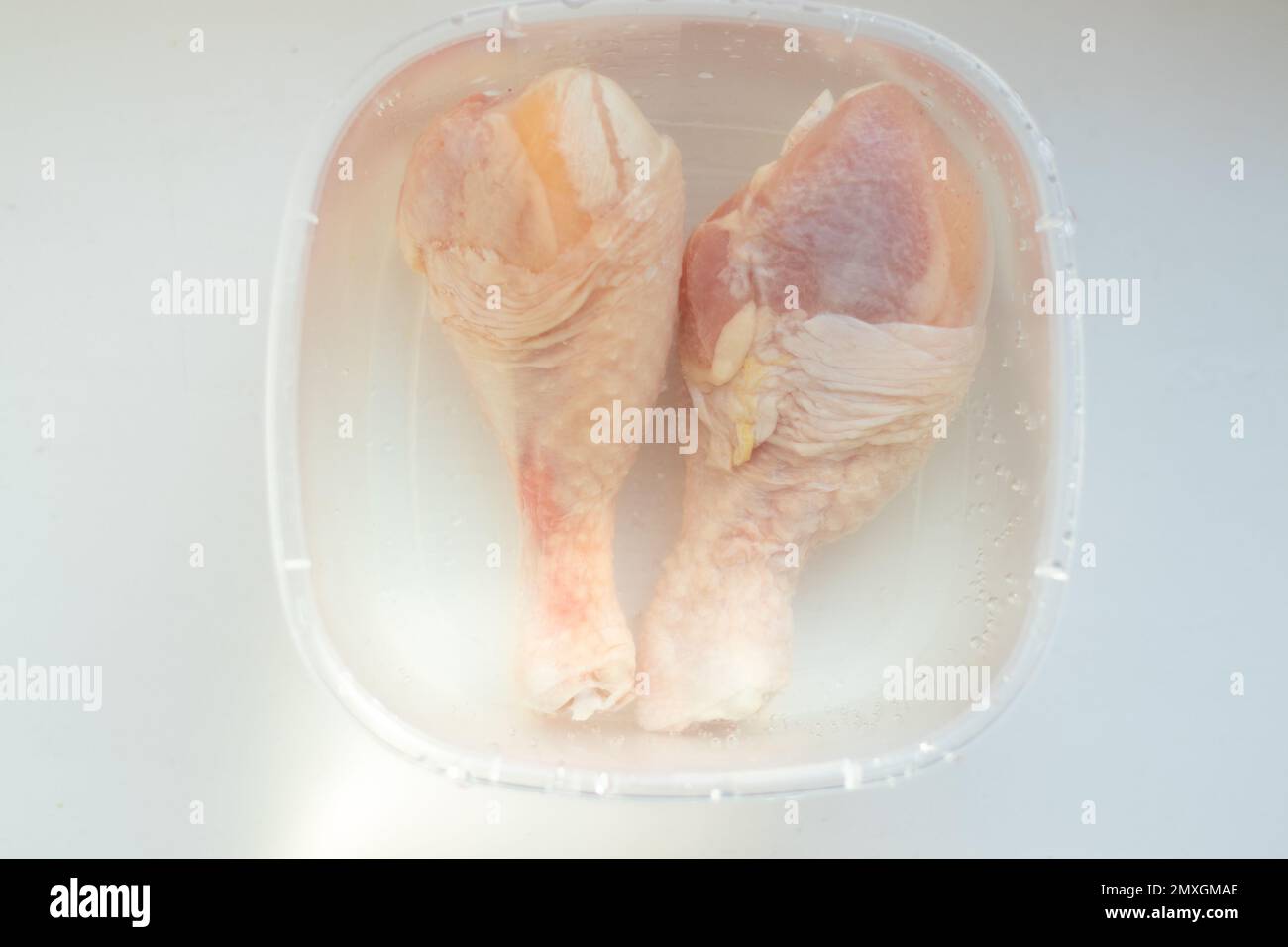 due bastoncini di pollo crudi si trovano in un piatto con acqua Foto Stock