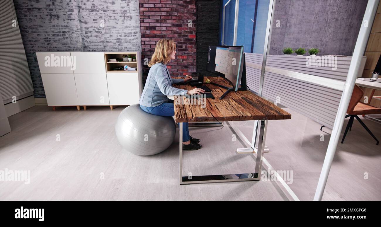 Correggere la postura alla scrivania in ufficio usando la sfera di idoneità Foto Stock