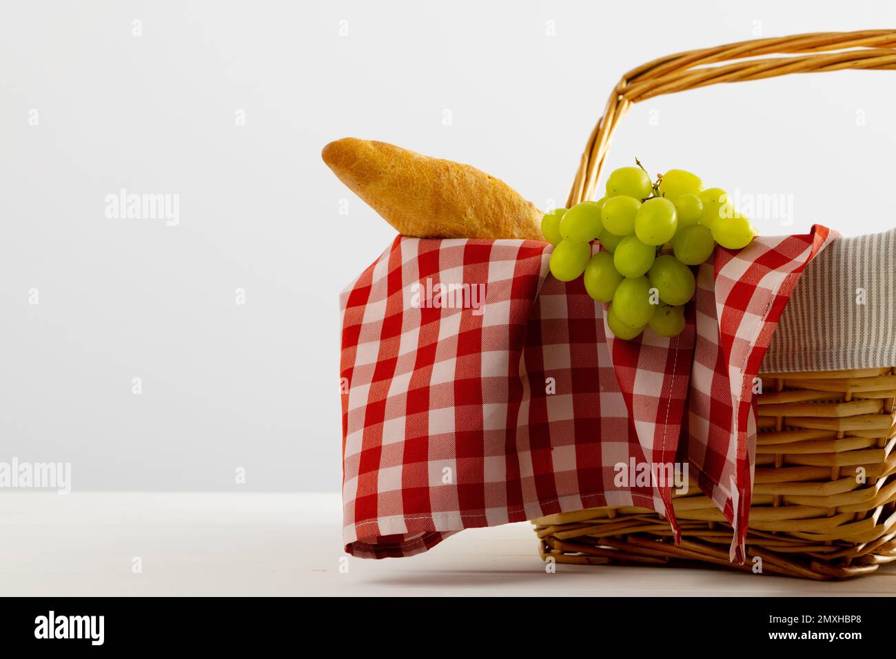 Cestino da picnic con tessuto vichy rosso e bianco e cibo su sfondi bianchi Foto Stock