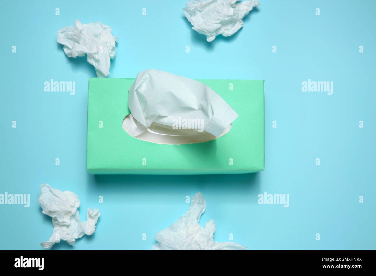 Fazzolettini di carta usati e scatola su sfondo azzurro, piatto Foto Stock