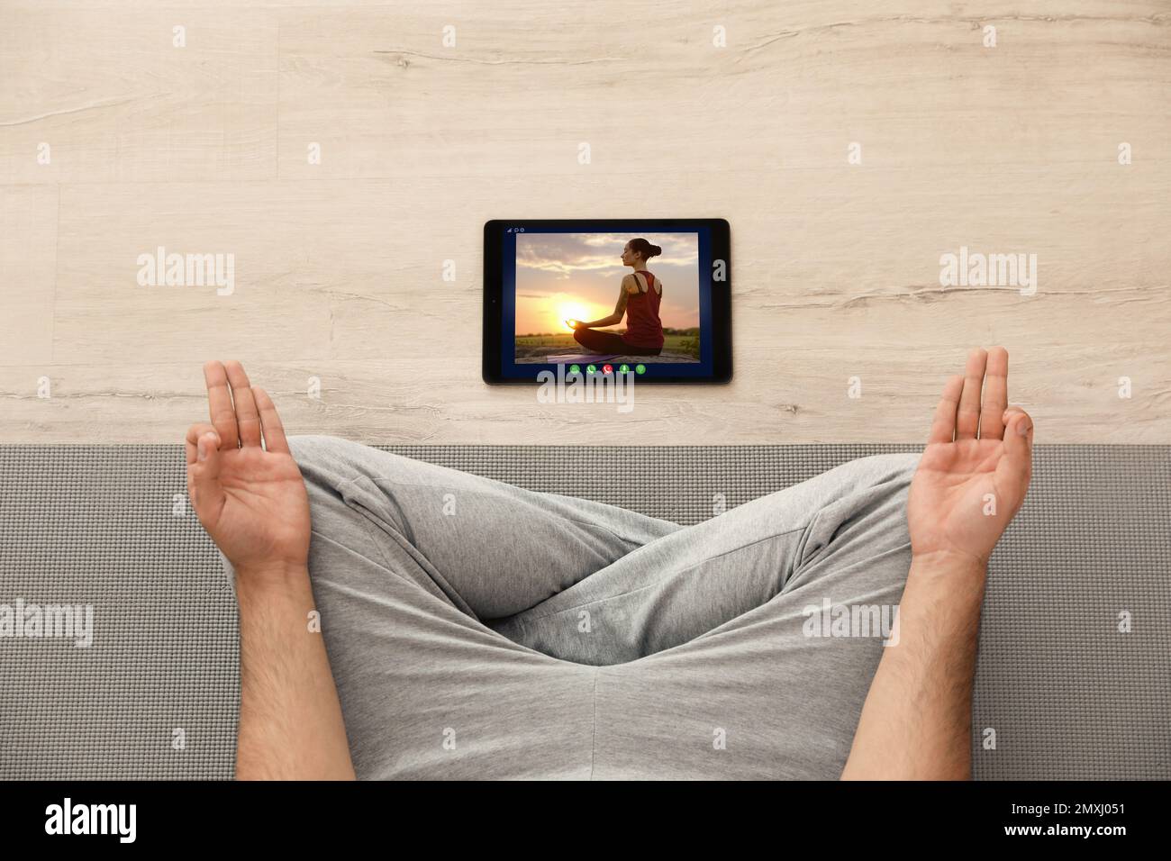 Corso di yoga a distanza durante la pandemia di coronavirus. Uomo che pratica online con l'insegnante tramite tablet a casa, vista dall'alto Foto Stock