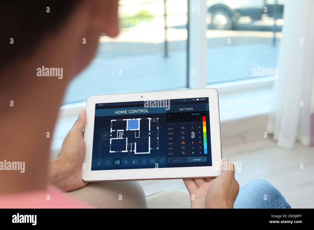 Donna che utilizza il sistema di controllo domestico a risparmio energetico su tablet, primo piano Foto Stock