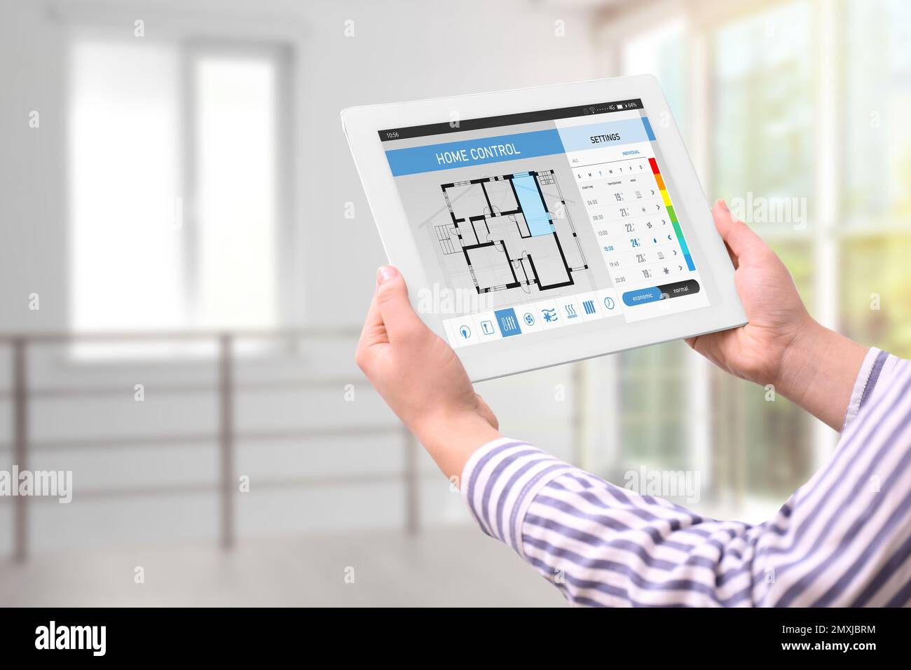 Donna che utilizza il sistema di controllo domestico a risparmio energetico su tablet, primo piano Foto Stock