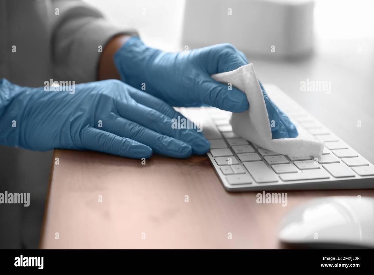 Donna in guanti di lattice pulizia tastiera computer con salviette bagnate  a tavolo, primo piano Foto stock - Alamy