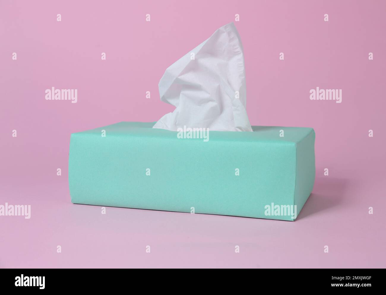 Scatola con fazzolettini di carta su sfondo rosa Foto Stock