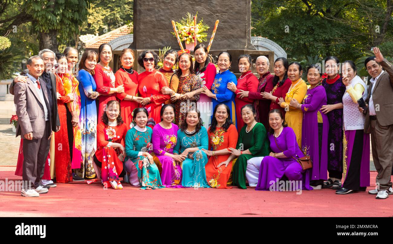 Un grande gruppo di donne vietnamite vestite di colorato tradizionale ao dai, insieme ad alcuni uomini, che sono membri di un club culturale, posare per un gr Foto Stock