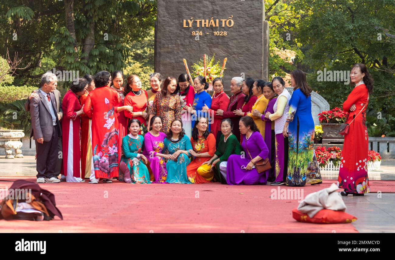 Un grande gruppo di donne per lo più vietnamite vestite di colorato tradizionale ao dai, si organizzano per posarsi per una foto di gruppo nel centro di Hanoi, Vietn Foto Stock