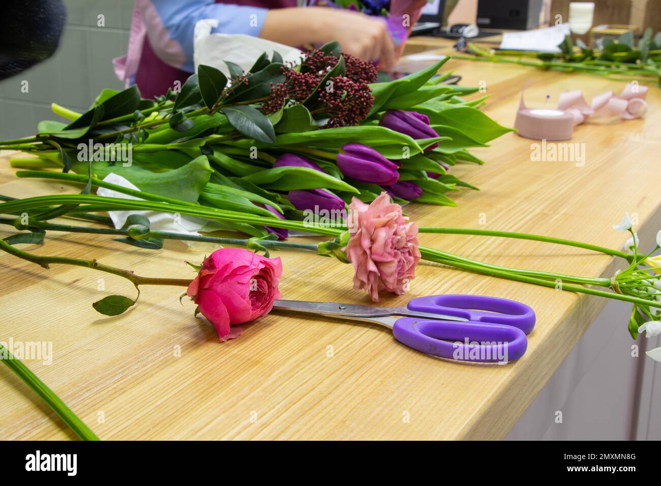 forbici per il taglio dei fiori giacciono su un tavolo con fiori in un negozio di fiori Foto Stock