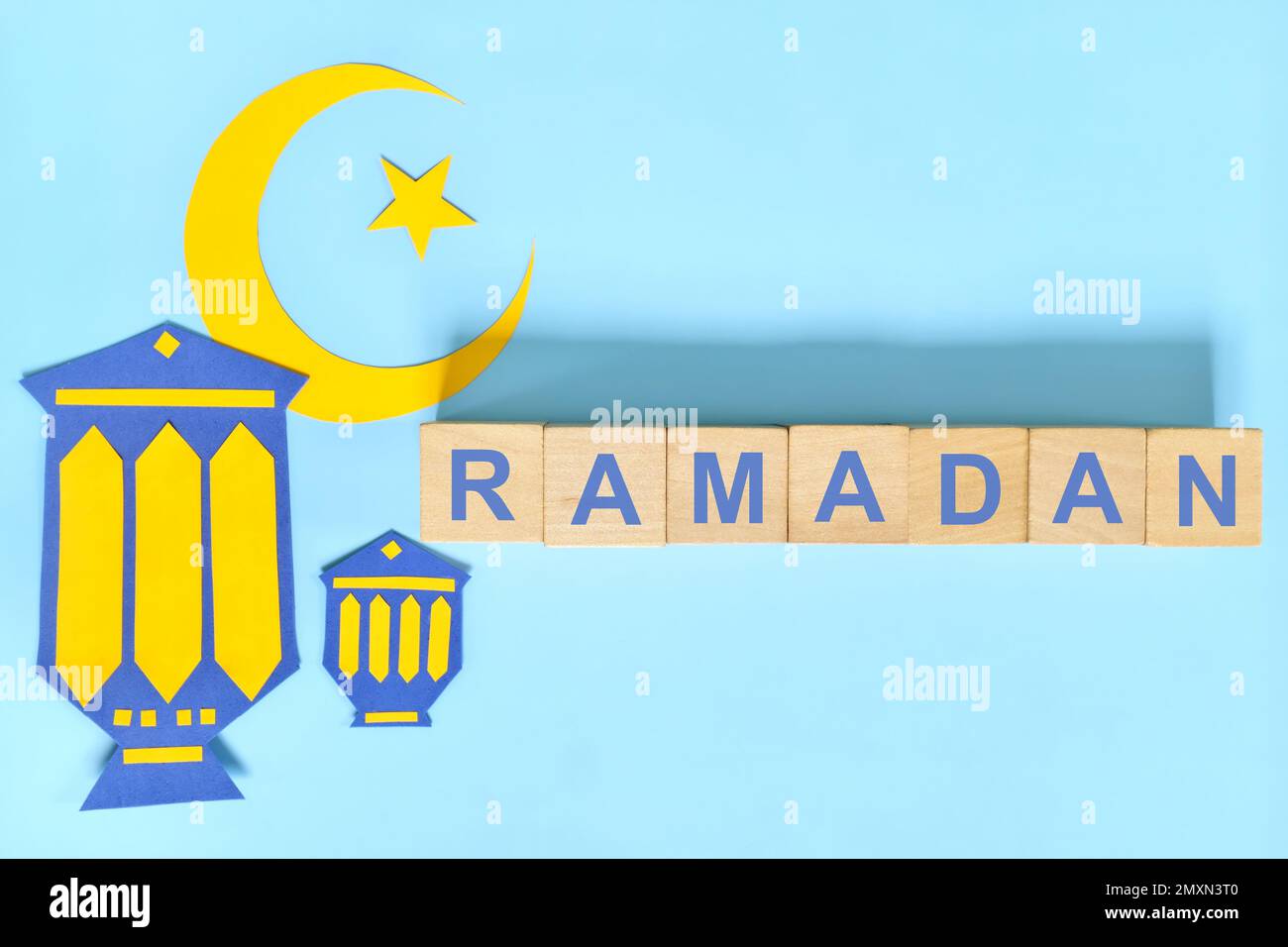 Luna di Crescent, stella e lanterna decorazione con testo su blocchi di legno piatto giacente su sfondo blu. Ramadan Kareem celebrazione del mese santo islamico. Foto Stock