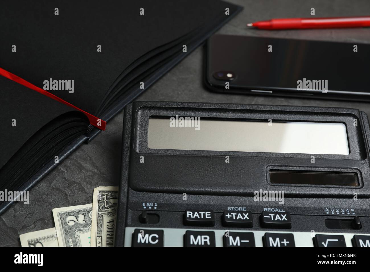 Calcolatrice, denaro, smartphone e notebook su tavolo grigio scuro, primo piano. Contabilità fiscale Foto Stock