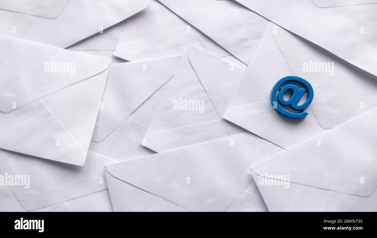 Concetto di vendita del email. Una pila di buste bianche e il simbolo dell'indirizzo e-mail. Foto Stock