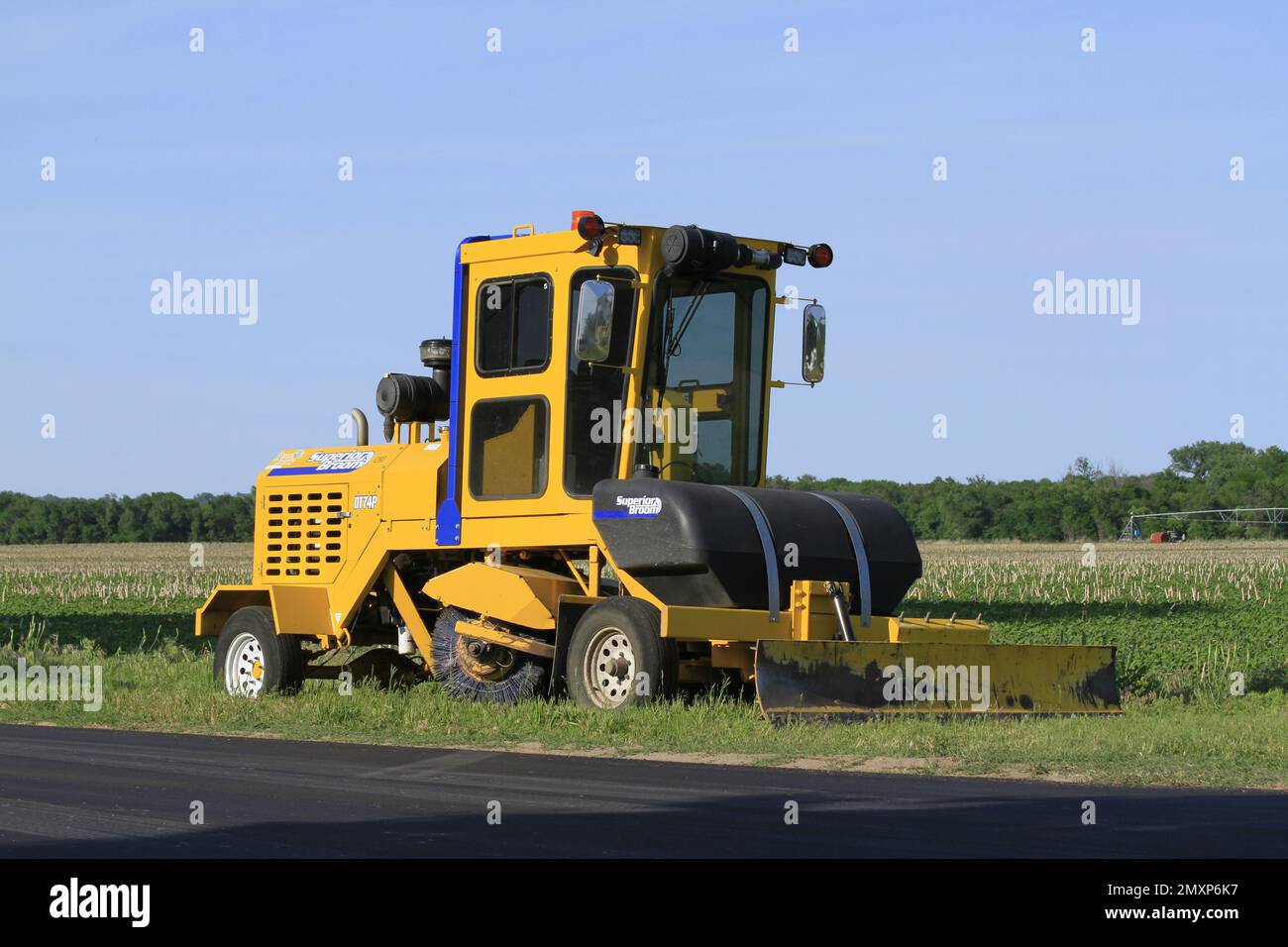 Foto di una spazzatrice Superior su una strada con cielo blu e campo agricolo Foto Stock