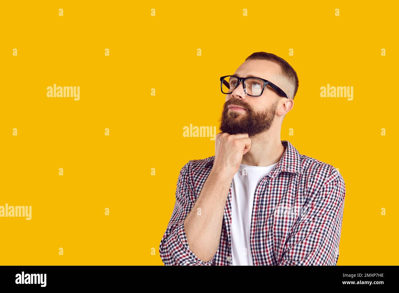 L'uomo in occhiali pensando a qualcosa e guardando via lo sfondo giallo dello spazio della copia Foto Stock