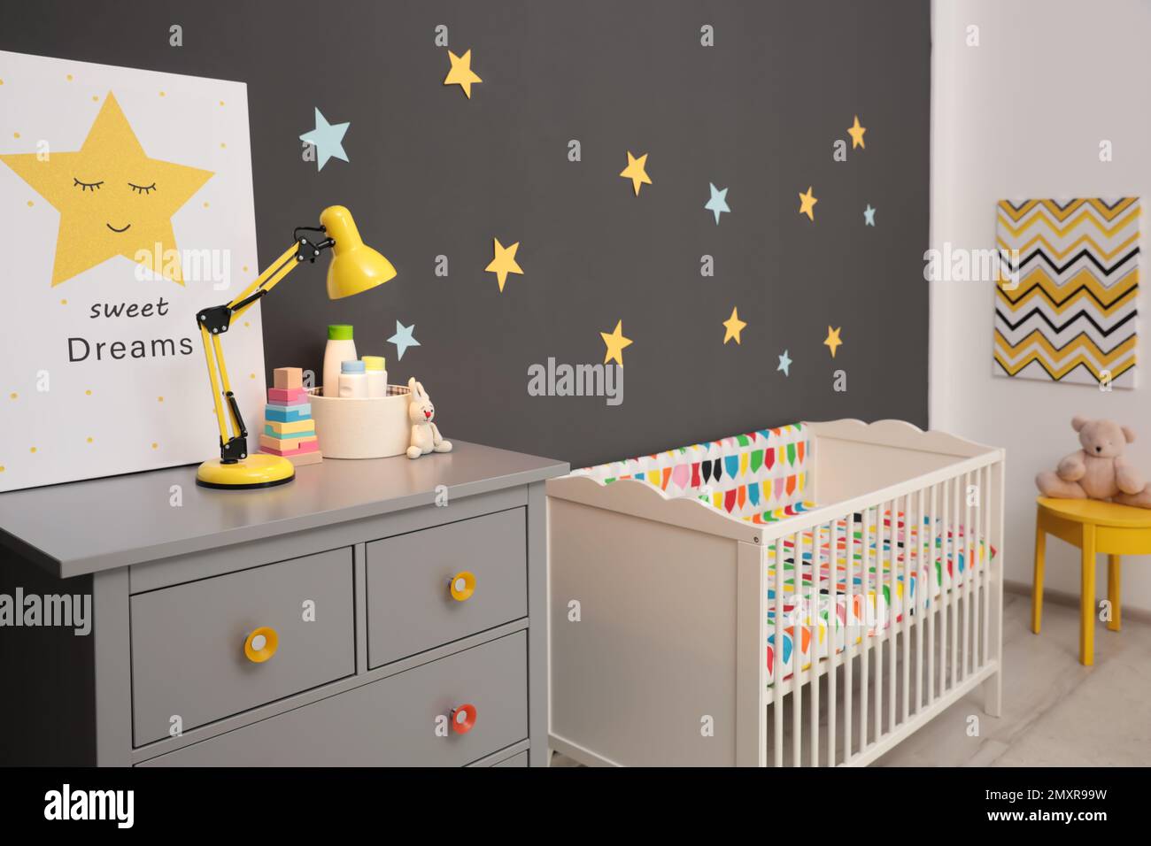 Carino interno della stanza del bambino con la culla moderna vicino alle stelle sulla parete Foto Stock