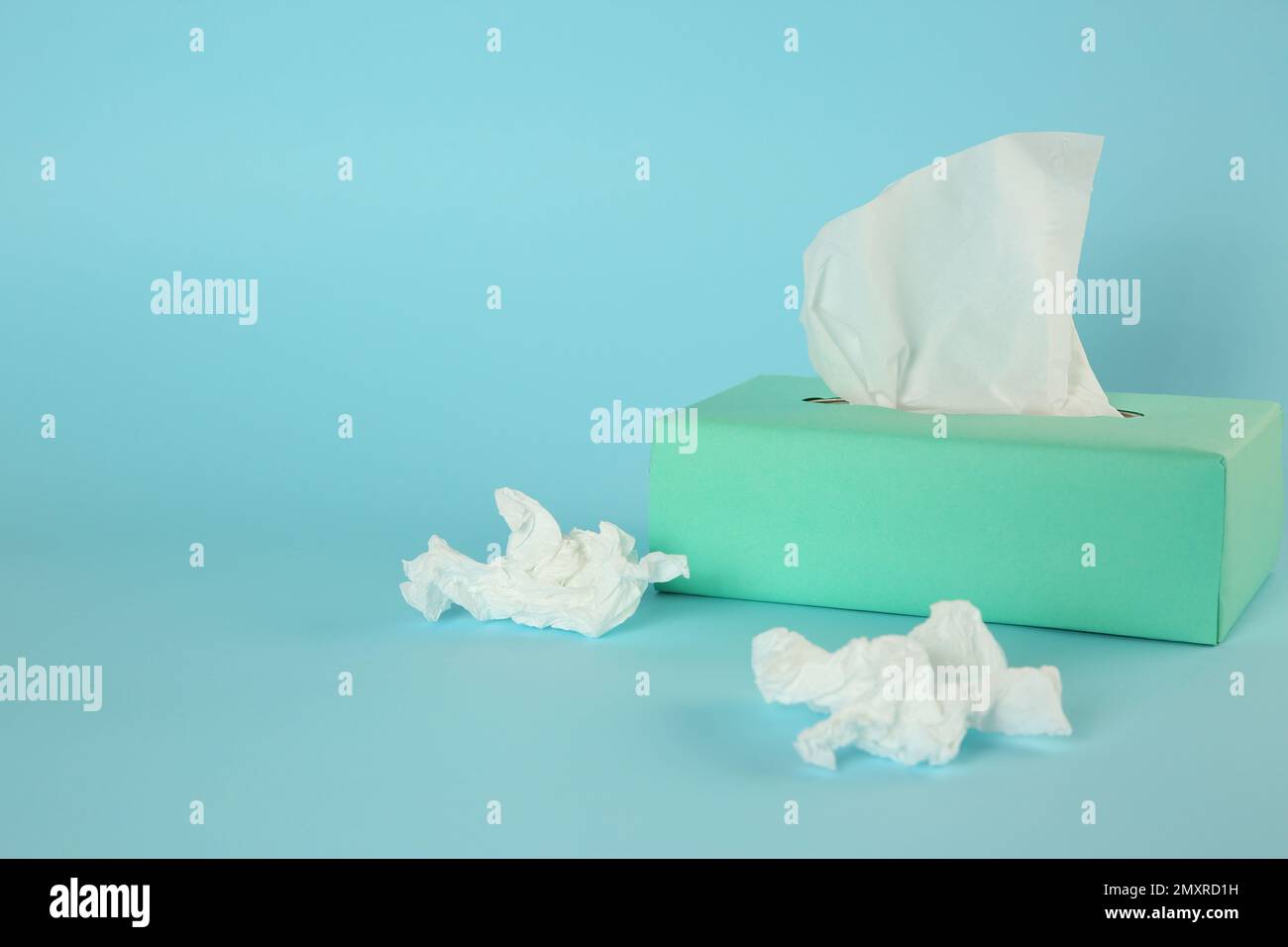 Fazzolettini di carta usati e scatola su sfondo azzurro. Spazio per il testo Foto Stock