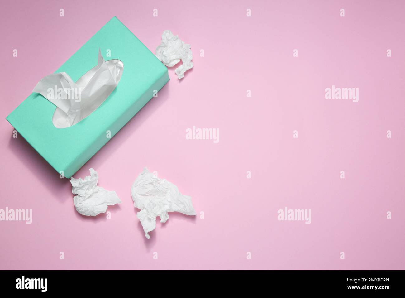 Fazzolettini di carta usati e scatola su sfondo rosa, piatto. Spazio per il testo Foto Stock