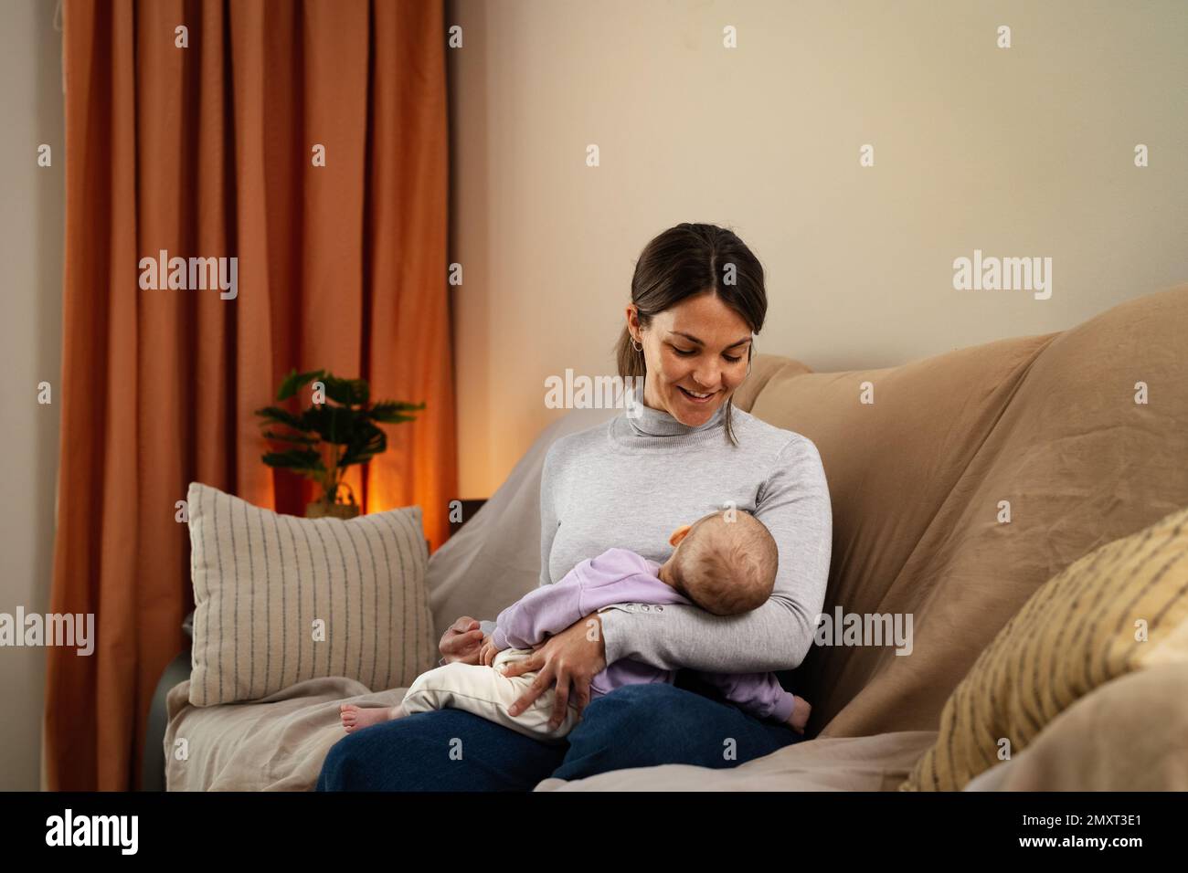 Madre felice che si prende cura del suo bambino piccolo che dorme nelle sue braccia a casa - famiglia di concetto e maternità Foto Stock